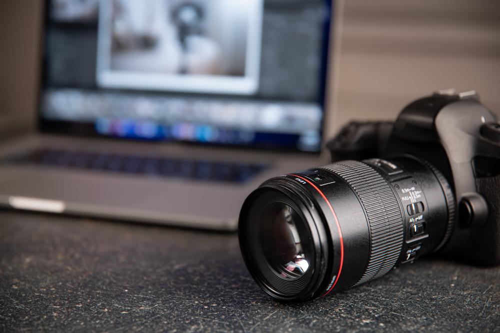 professional camera sitting on table with computer in the background